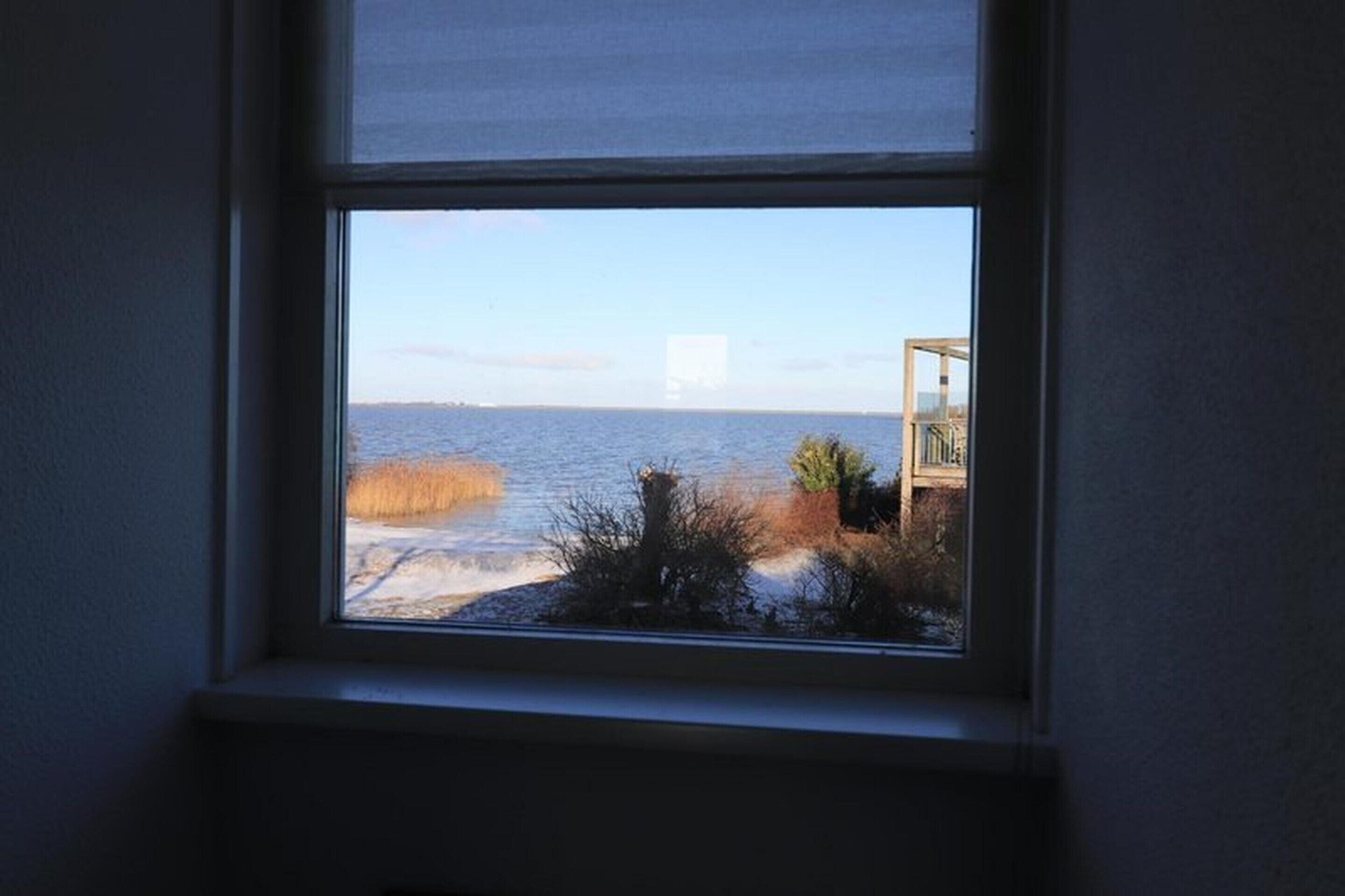 A window with a view of a body of water and a distant building.
