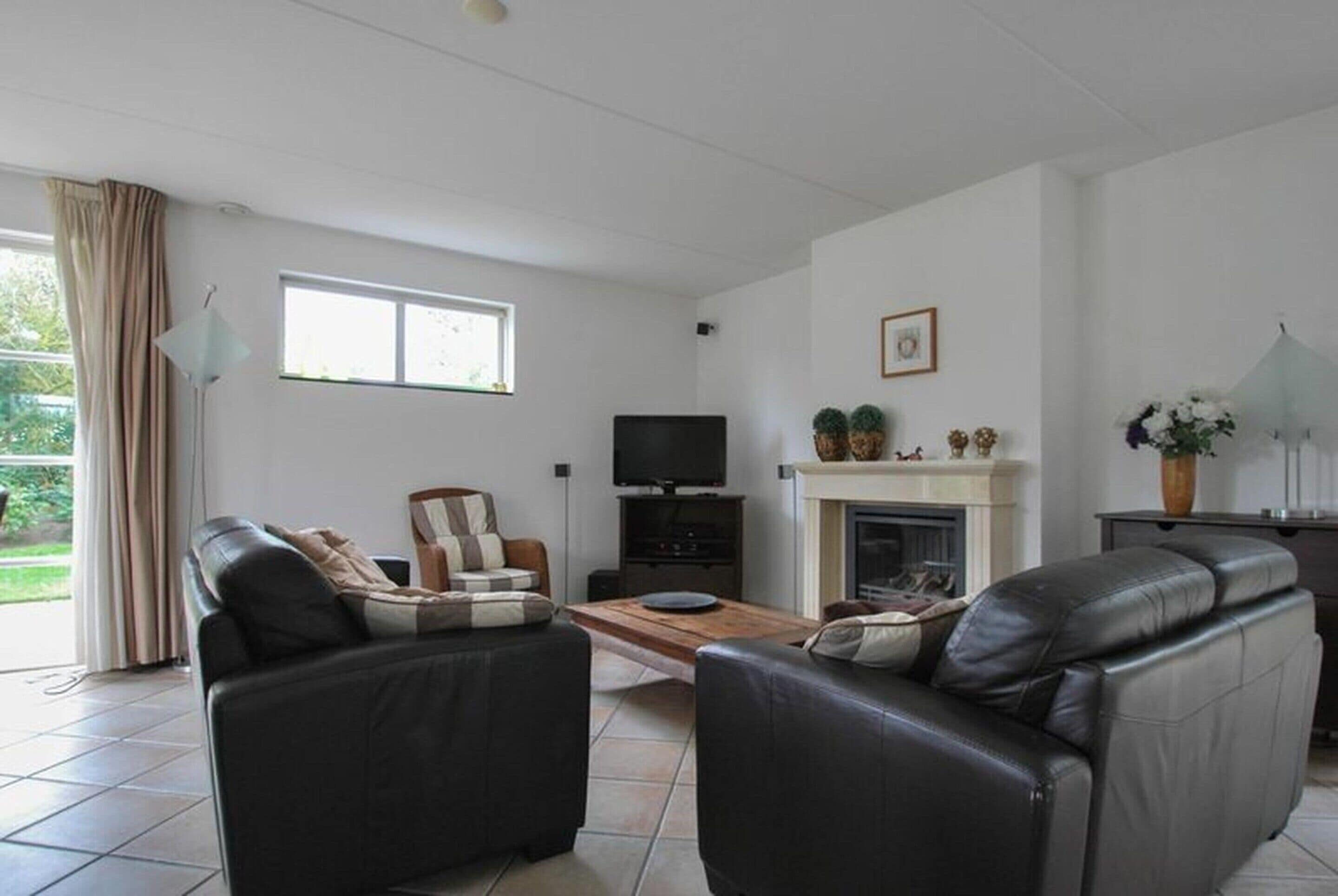 A living room with two black leather sofas, a wooden coffee table, a television, and a fireplace.