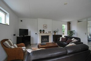 A living room with a fireplace, a television, a sofa, and a coffee table. - Beachside Dune Villa With Garden (Makkum)