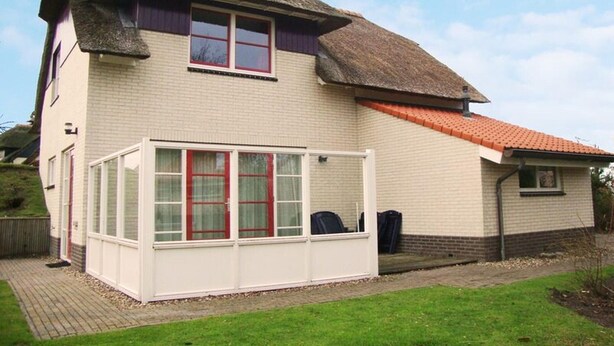 A two-story house with a thatched roof and a conservatory. - Beachside Dune Villa With Garden (Makkum)