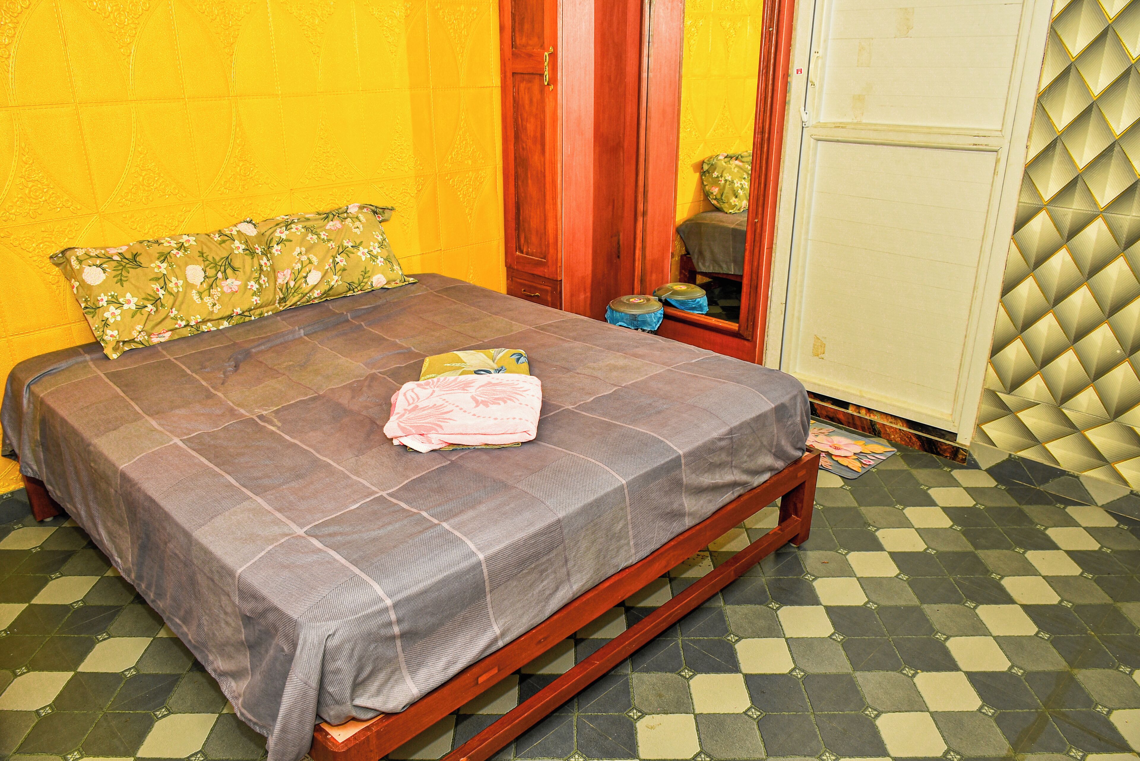 Ein Bett mit karierter Bettdecke, einem Blumenkissen und einer gefalteten Decke auf einem Holzrahmen.