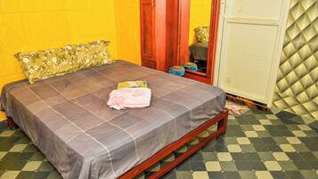 Ein Bett mit karierter Bettdecke, einem Blumenkissen und einer gefalteten Decke auf einem Holzrahmen.