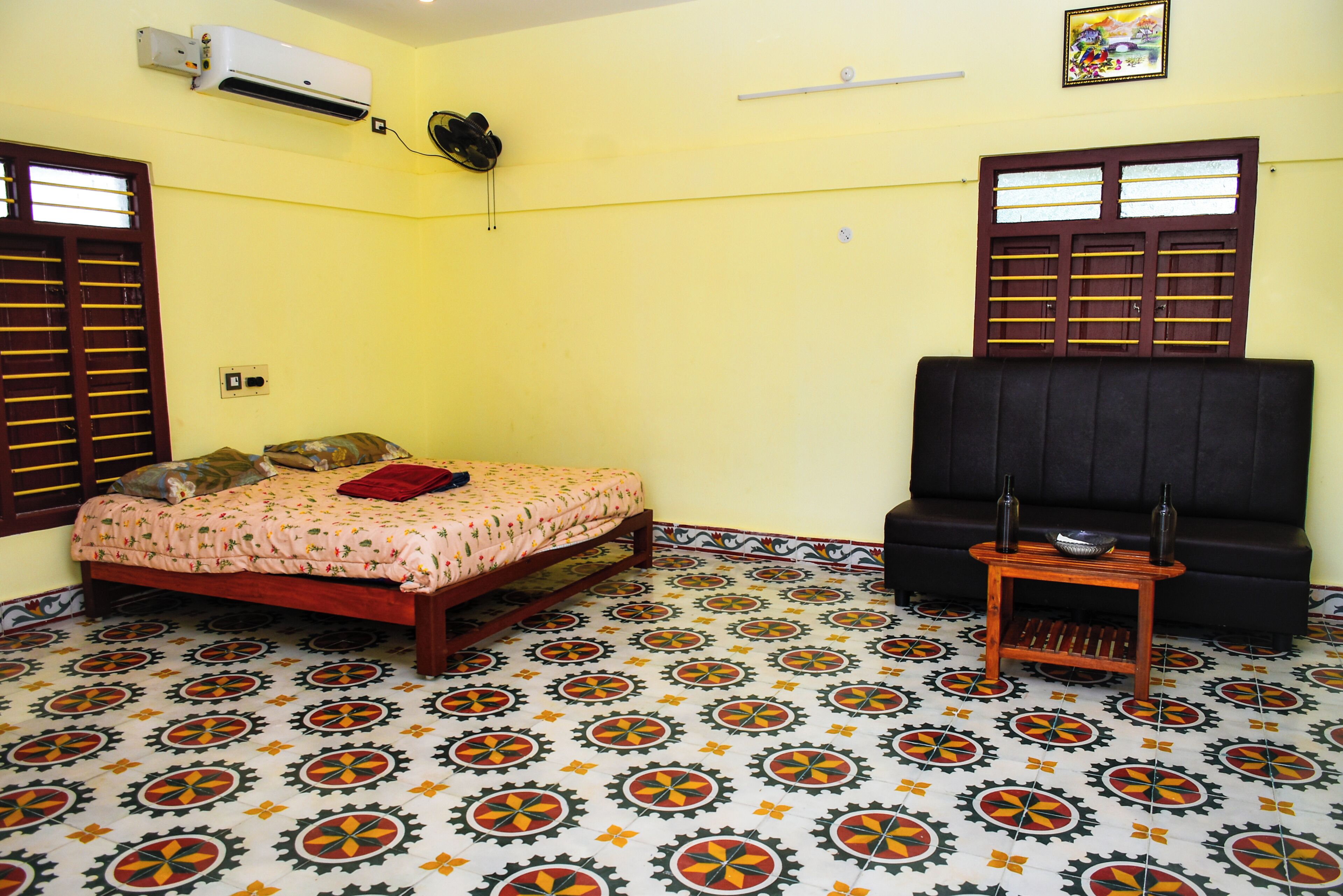 Una habitación con cama, sofá, una mesita y suelo estampado.