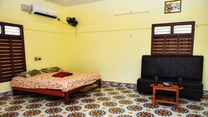 Una habitación con cama, sofá, una mesita y suelo estampado.