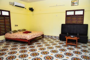 Una habitación con cama, sofá, una mesita y suelo estampado.