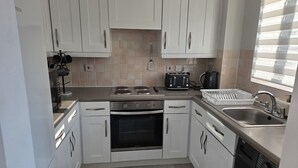 Een moderne keuken met witte kasten, een inbouwoven, een vaatwasser en een broodrooster.