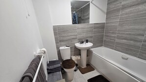 Een badkamer met toilet, wastafel en bad.