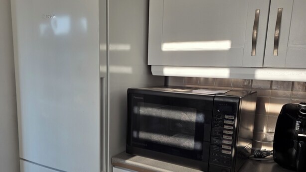 Una cocina con un refrigerador blanco, un microondas negro y una cafetera sobre la encimera.