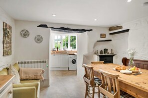 A cozy kitchen with a dining area, a washing machine, and a view of the outdoors. - River Avon Stay for Four (Totnes)