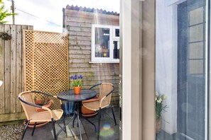A patio area with a round table, four wicker chairs, and a potted plant. - Modern Studio Near Port Isaac (Bodmin)
