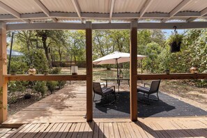 A covered patio with a table and chairs, surrounded by a wooden deck and a view of a garden. - 4 Bdrm, Spacious, Pool, Patio, Yard Games (Austin)