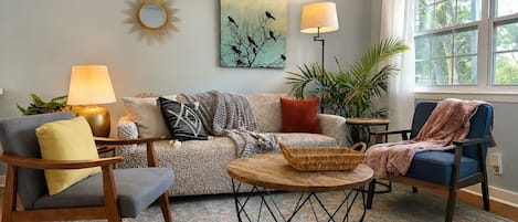 A living room with a sofa, two armchairs, a coffee table, and a lamp.