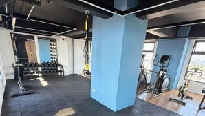A gym with exercise equipment, a blue pillar, and a window. - Capihome (Ciudad de Guatemala)