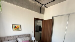 Ein Schlafzimmer mit Bett, Kissen, Nachttisch, Lampe, Kleiderschrank und einem Bild an der Wand.