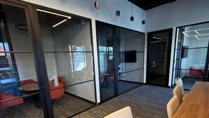 A modern conference room with glass walls, a long wooden table, and a few chairs. - Capihome (Ciudad de Guatemala)