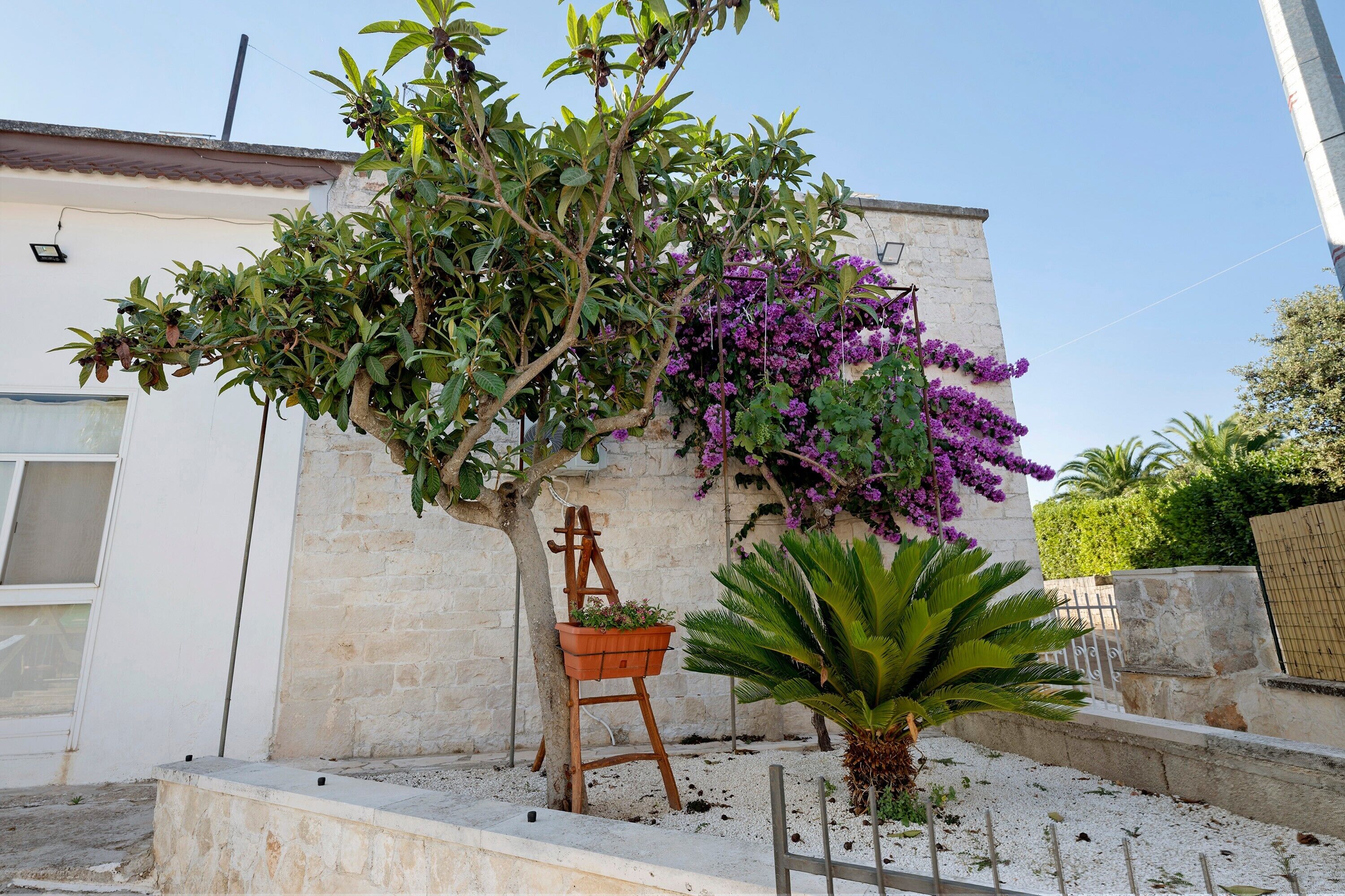 A garden with a tree, a planter with flowers, and a wooden easel.