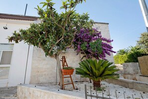 Ein Garten mit Baum, einem Blumenbeet und einer hölzernen Staffelei.
