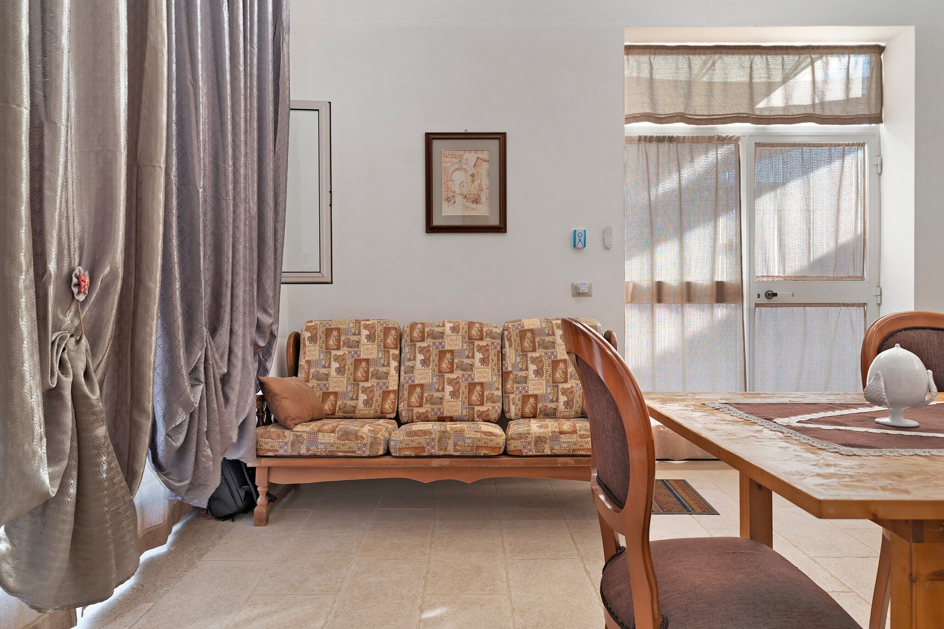 A living room with a sofa, a dining table, and a window with curtains.