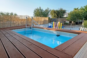 Une piscine rectangulaire entourée d’une terrasse en bois.