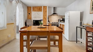 Eine Küche mit einem Holztisch, Stühlen, einem Herd und einem Kühlschrank.