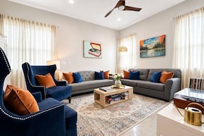 A living room with a sofa, armchair, coffee table, and decorative items. - 2-Home Austin Compound | Hot Tub + Cowboy Pool (Austin)