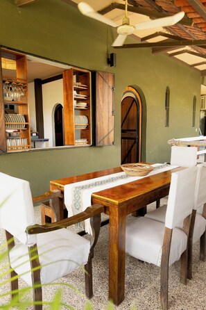 A dining area with a wooden table, white upholstered chairs, and a ceiling fan. - Beautiful home in La Punta with a private pool, rooftop terrace, and AC. (Puerto Escondido)