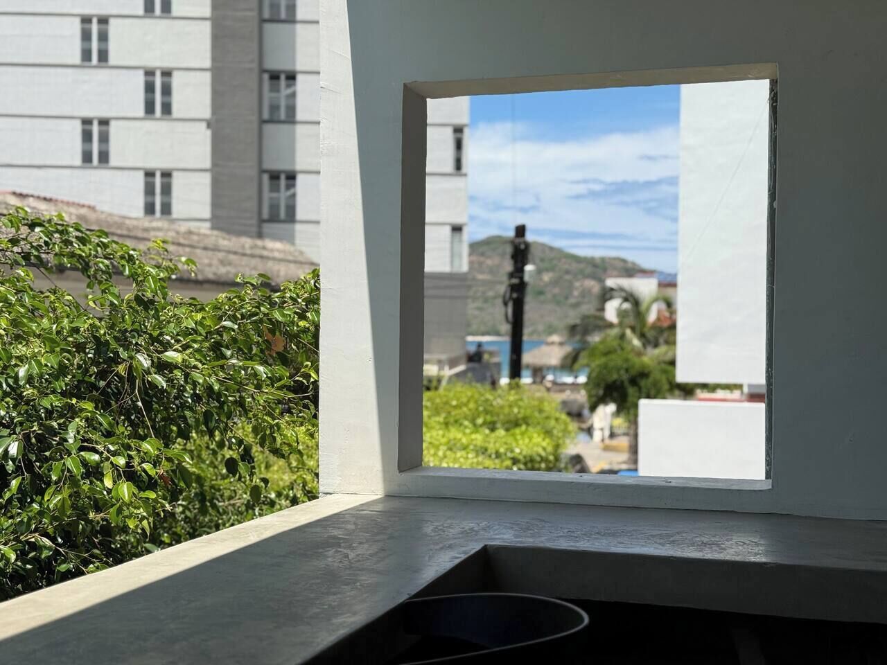 A window with a view of a building and greenery.