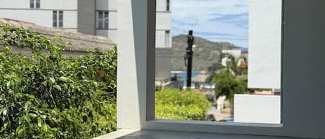 A window with a view of a building and greenery.