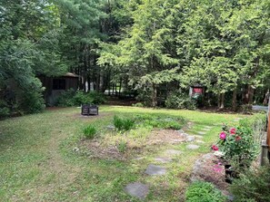 A garden with a wooden structure, stone stepping stones, and a variety of plants.