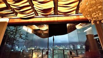 A balcony with a city view, a glass partition, and wicker furniture.