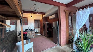 A compact kitchen with a dining area, a refrigerator, and a ceiling fan.