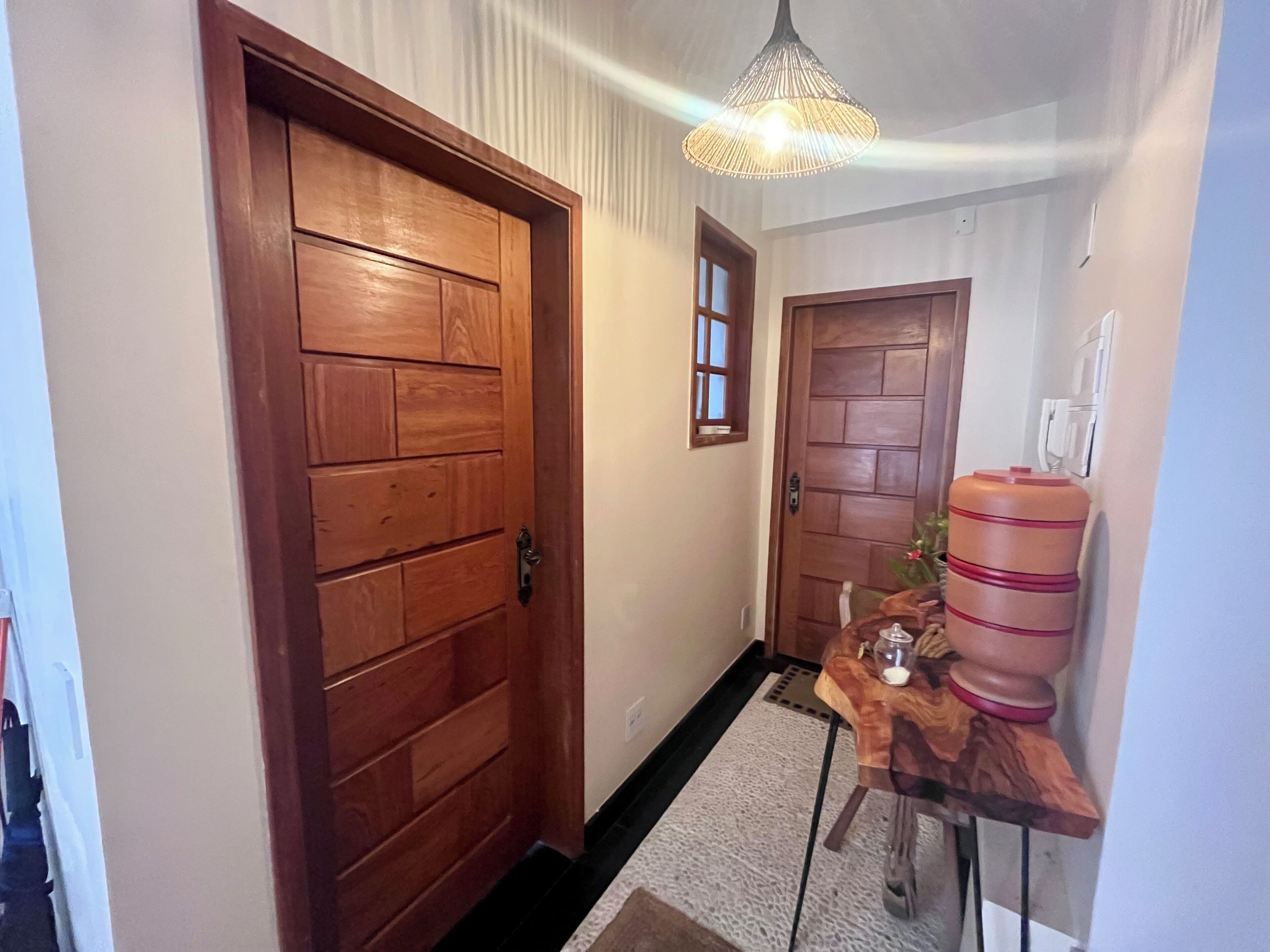A hallway with wooden doors, a small table with a water dispenser, and a hanging light fixture.