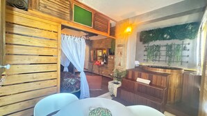 Ein Zimmer mit einem Bett, einem Tisch mit Obstschale, einer Holzwand und einer an der Wand befestigten Pflanze.