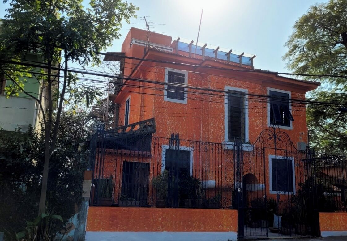 A two-story building with a red facade, a gated entrance, and a visible roof with a skylight.