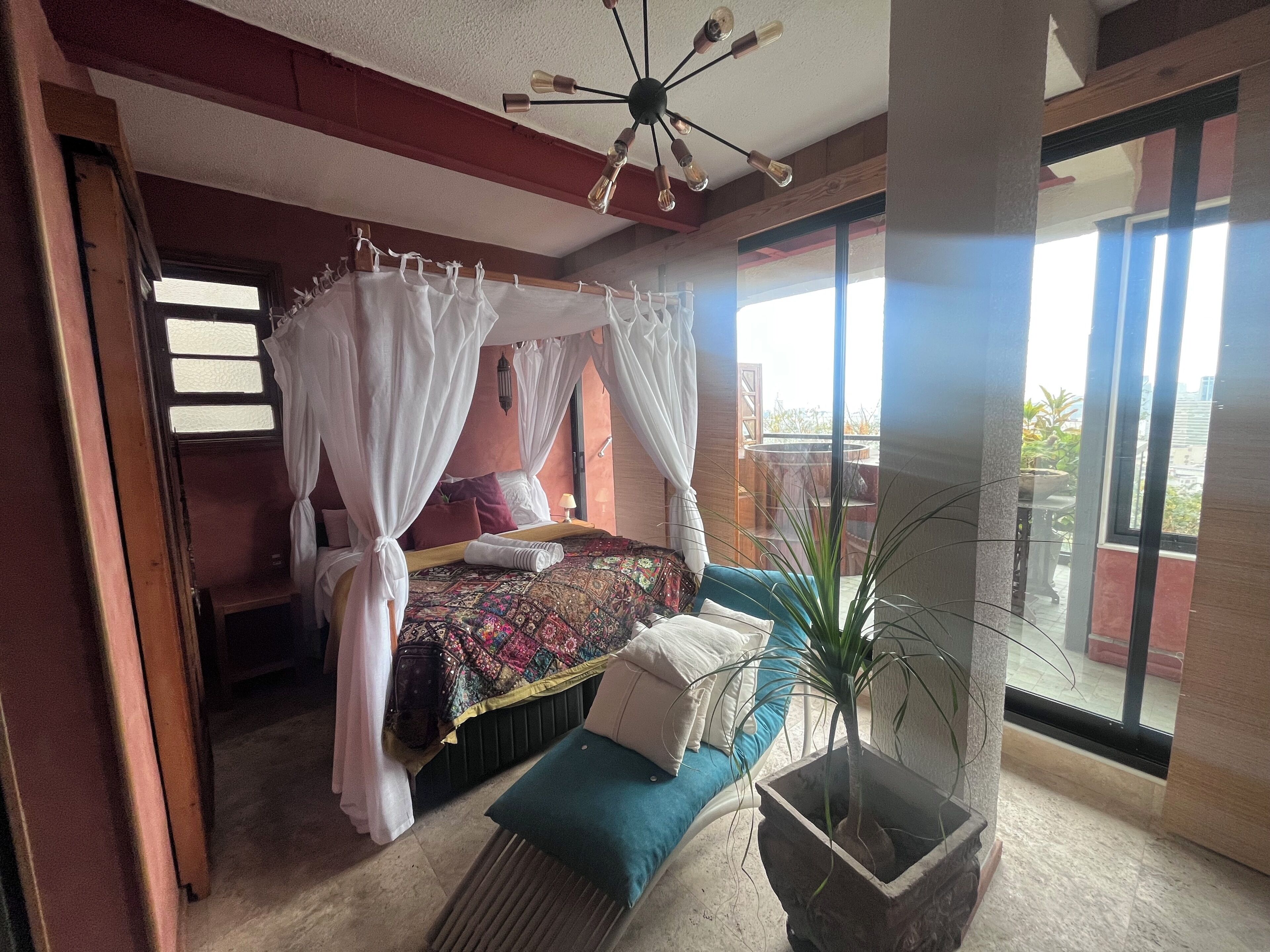 Quarto com cama de dossel, planta em vaso e varanda com vista.