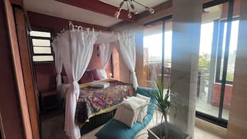 Quarto com cama de dossel, planta em vaso e varanda com vista.