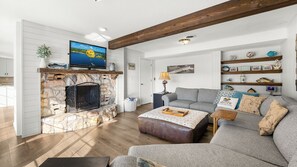 Ein Wohnzimmer mit Kamin aus Stein, einem Fernseher, einer Couch und einem Couchtisch.