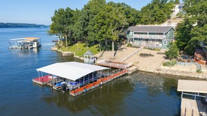 Une propriété au bord du lac, dotée d’un quai, d’un abri pour bateaux et d’une maison avec une terrasse.