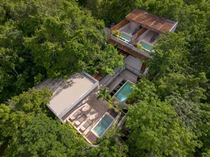 Une maison à deux étages avec une piscine, entourée d’une végétation luxuriante.