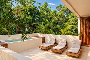 Une terrasse sur le toit dotée d’un jacuzzi, de chaises longues en bois et d’une végétation luxuriante.