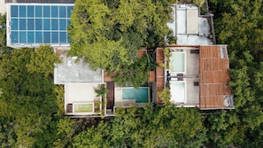 An aerial view of a resort with multiple swimming pools, a large blue solar panel, and lush greenery. - Remodeled 4BR Boho Villa · Pool Trilogy + Hot Tub (Tulum)