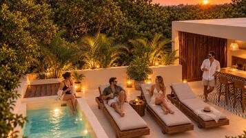 A poolside area with lounge chairs and a pool, surrounded by greenery and a sunset view.