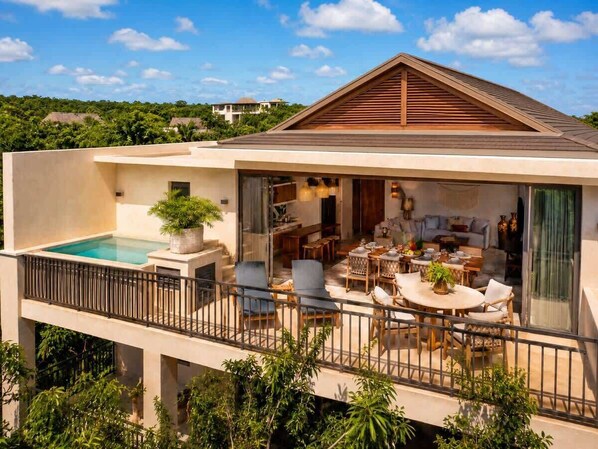 A modern two-story house with a swimming pool, outdoor seating area, and a balcony. - Penthouse| Private Pool| Hot & Cold Plunge + Spa (Tulum)
