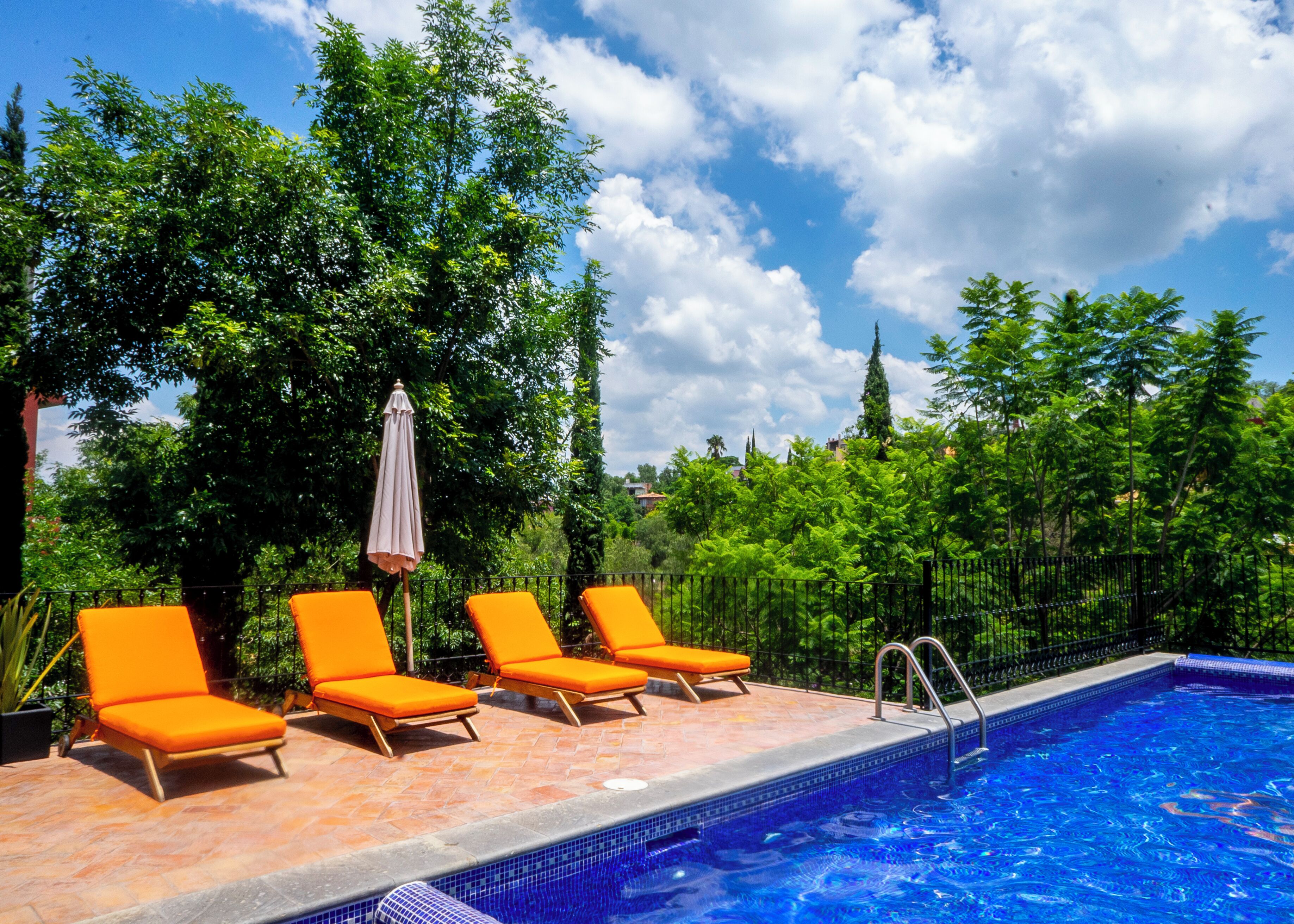 A swimming pool with lounge chairs and an umbrella.