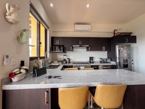 A modern kitchen with dark cabinets, a granite countertop, and a built-in stove. - Lujo y confort capilla SM de Allende (San Miguel de Allende)