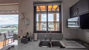 A kitchen with a large window, granite countertops, a sink, and a microwave. - Lujo y confort capilla SM de Allende (San Miguel de Allende)