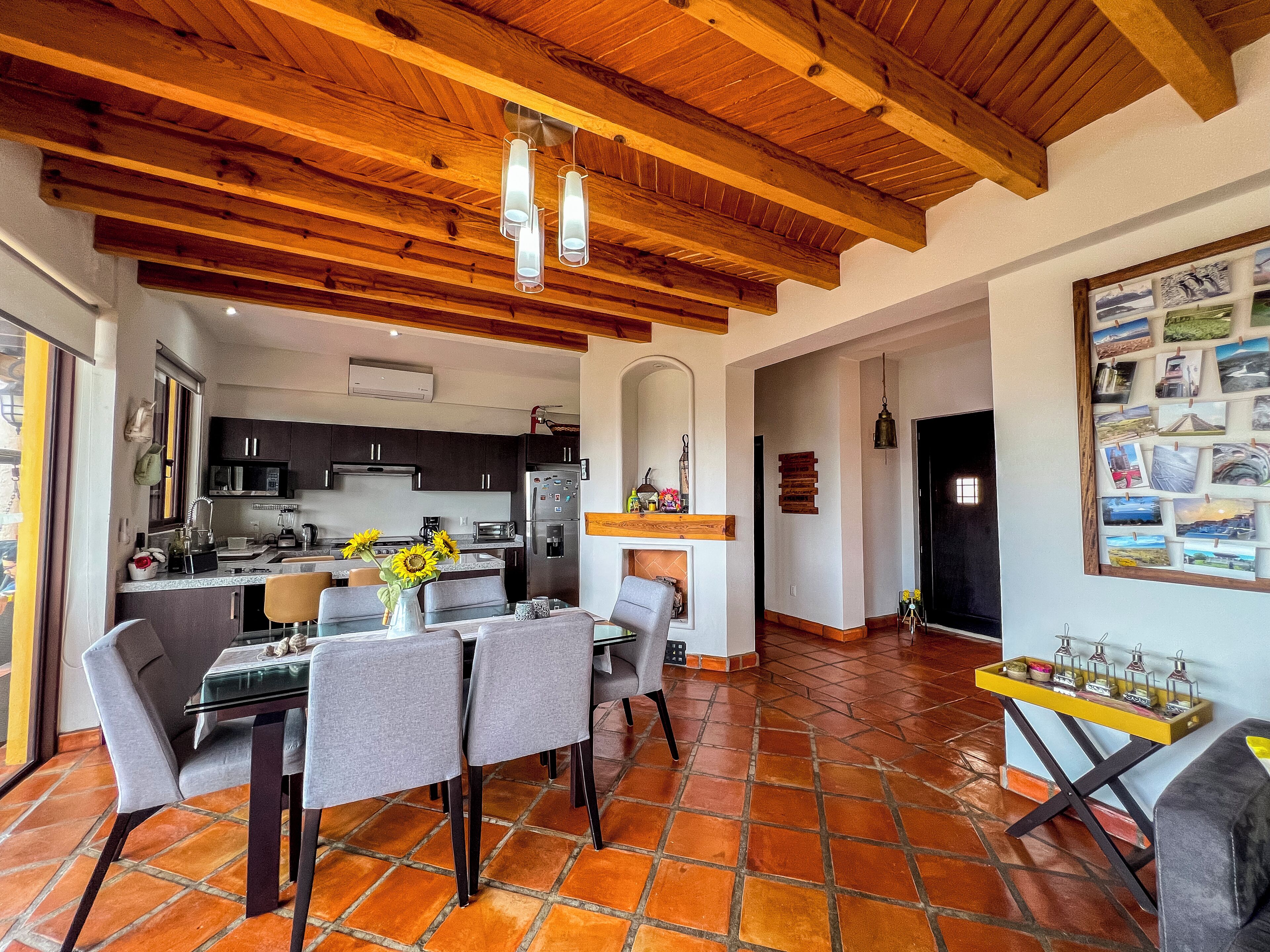 A spacious living area with a dining table, chairs, and a kitchen in the background.
