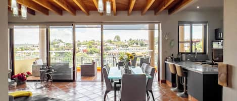 A spacious dining area with a high ceiling and large windows offering a view of the city.