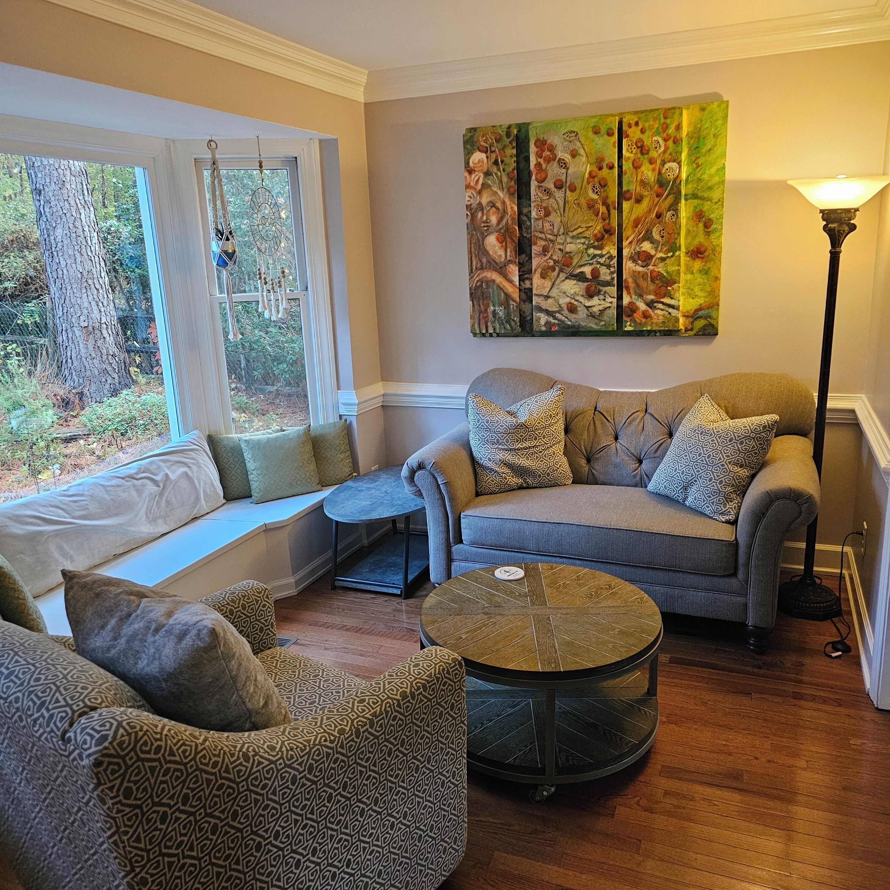 A cozy living room with a sofa, armchairs, a coffee table, and a painting on the wall.