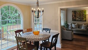A dining area with a round table, chairs, a chandelier, and a view through a large window. - 3-bedroom house in Durham near UNC, Duke and the American Tobacco Trail (Durham)